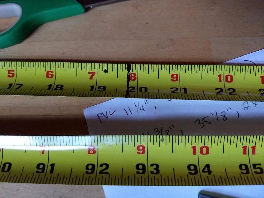 Two pieces of tape measure lying side by side: one is marked and ready to be cut, the other unmarked.